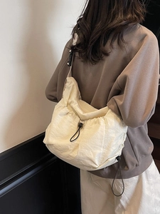 Minimalist cream pleated crossbody bag with drawstring design and wide shoulder strap