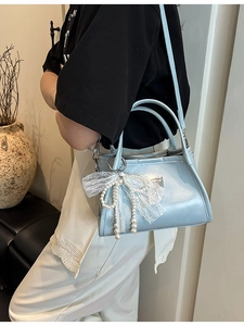 Elegant light blue faux leather shoulder bag with a large white lace bow pendant