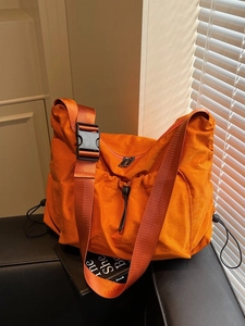 Vibrant orange nylon pleated shoulder bag with adjustable strap and large capacity design