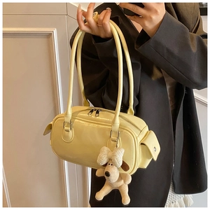 Détail d'un sac Boston en similicuir crème avec un pendentif chien en peluche mignon
