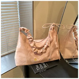 Dettaglio della borsa a spalla rosa plissettata con trama satinata e fiocco laterale