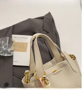 Close-up of litchi textured leather bucket bag with gold hardware and woven pendant