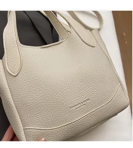 Close-up of cream textured leather bucket bag with embossed fashion brand lettering