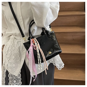Détail d'un mini sac cabas noir avec motifs de chiens gaufrés et rubans en dentelle