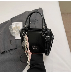Détails d'un sac à main noir brillant avec logo argenté et pendentif de tennis unique
