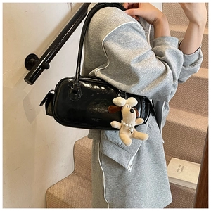 Détail d'un sac Boston en cuir verni noir brillant avec un pendentif chien en peluche doux