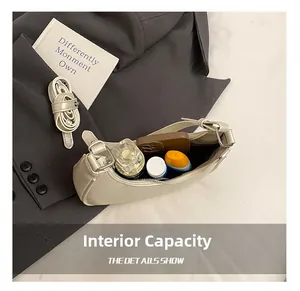 Internal capacity of cream leather crescent bag showing phone and cosmetics