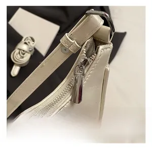 Detailed close-up of premium silver zipper and leather texture on a beige crescent bag