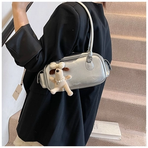 Détail du sac à main argenté métallisé avec breloque chien perle sur une tenue blazer noir