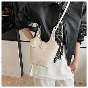 Dettaglio borsa a secchiello in pelle beige con motivo litchi e logo inciso sulla tracolla