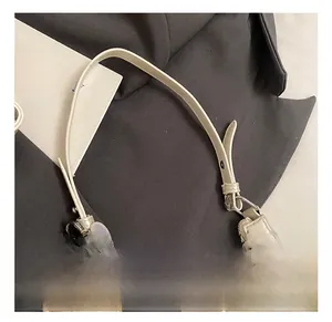 Detail view of cream white French baguette bag featuring heart and pearl charms