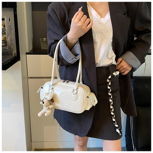 Sac Boston chic blanc cassé avec breloque chien en peluche dans un cadre moderne