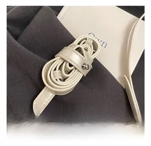 Detail view of adjustable cream faux leather shoulder strap with silver metal buckle
