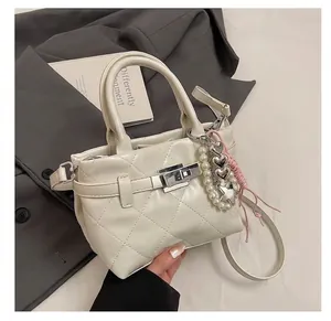 Détail du sac seau matelassé crème avec fermoir rotatif argenté et breloques perles