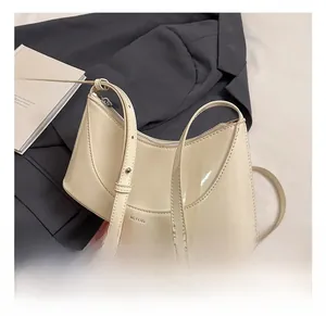 Detail view of cream patent leather crescent bag featuring NO FILTER lettering and silver zip
