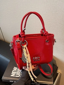 Mini sac à main rouge brillant avec poignée nouée et bandoulière sur des livres