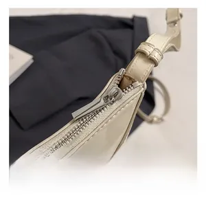 Detail of silver metal zipper on cream crossbody bag showing premium stitching and texture