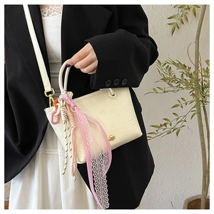 Détail d'un sac seau blanc gaufré avec ruban en dentelle et breloque chaîne colorée