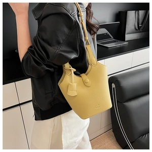Dettaglio borsa a secchiello gialla in pelle martellata con chiusura a bottone e logo