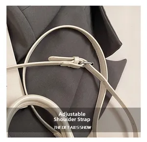 Détail de la bandoulière réglable en cuir beige avec boucle en métal argenté poli
