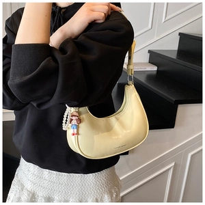 Detail view of yellow half-moon underarm bag with pearl charm and cute cartoon pendant