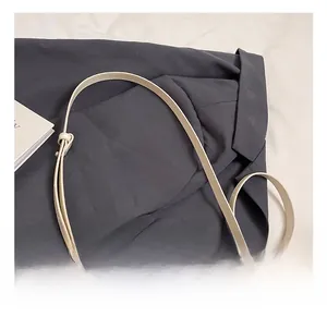 Detail of cream patent leather bag showing adjustable strap with silver metal buckle