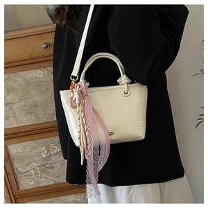 Détail du mini sac fourre-tout crème avec motifs en relief et ruban de dentelle rose