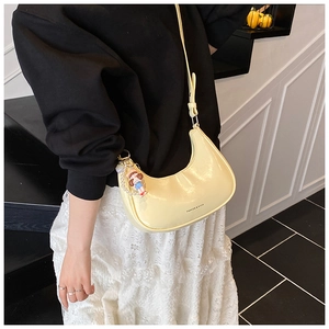 Light yellow crescent bag detail with glossy finish and cute cartoon doll charm accessory