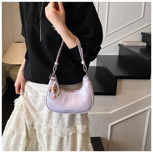 Detail of lavender crescent shoulder bag with pearl chain and doll charm accessory