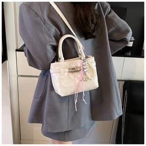 Détail du sac bandoulière matelassé blanc avec breloques de luxe et fermoir rotatif argenté