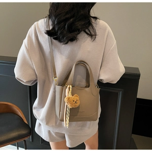 Taupe pebbled leather bucket bag shown from a back view on model with bear charm