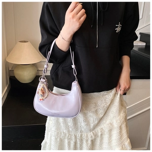 Close-up of purple patent leather half-moon bag with elegant pearl and doll charms