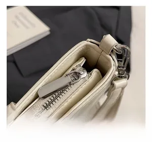 Detailed close-up of premium silver zipper and metallic hardware on a white leather bag