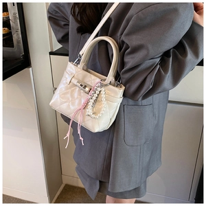 Détail du sac bandoulière blanc matelassé avec breloque perle et fermoir métallique
