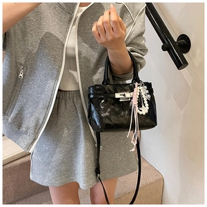 Détail du mini sac noir matelassé avec fermoir argenté et breloque cœur en perles