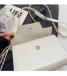 Detail of ivory square handbag with geometric flap and silver magnetic closure