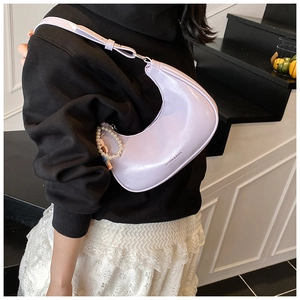 Detail of lavender crescent bag with glossy finish and pearl charm on shoulder strap