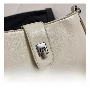 Close-up of silver metal twist lock and pleated oil wax leather texture on beige handbag