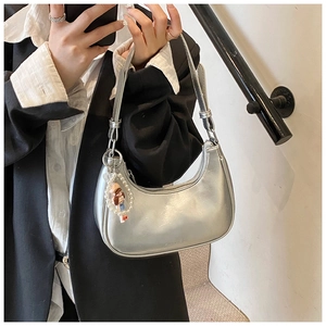 Detail of silver metallic dumpling bag with pearl cartoon charm and zipper closure