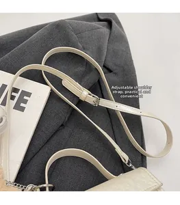 Detail of adjustable faux leather shoulder strap with silver buckle on beige crossbody bag