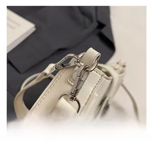 Detail of cream white textured leather bag featuring polished silver swivel metal hook