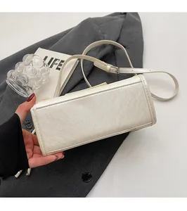 Detail of neat stitching on the bottom of a cream faux leather crossbody bag