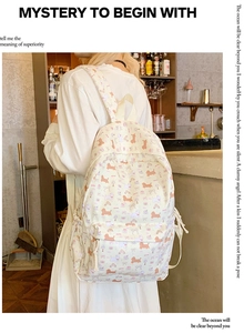 Detail of cream backpack with orange puppy and bow prints in a casual lifestyle setting