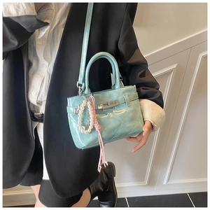 Détail du sac en cuir verni bleu clair avec surpiqûres en losange et breloque