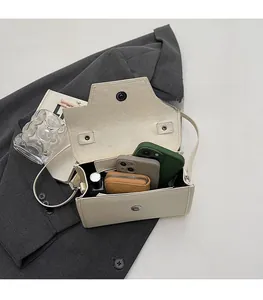 Interior view of beige crossbody bag showing space for phone and makeup on a grey blazer