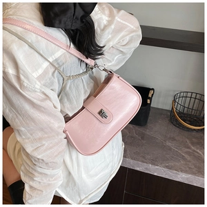 Detail of light pink faux leather shoulder bag with silver metallic buckle on a model