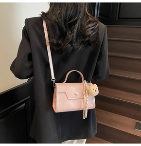 Detail of light pink pleated leather crossbody bag with teddy bear charm and silk scarf