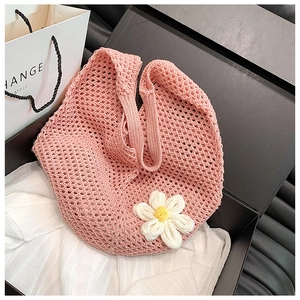 Detail der rosa Stricktasche mit weißer Häkelblume auf seidigem Hintergrundstoff