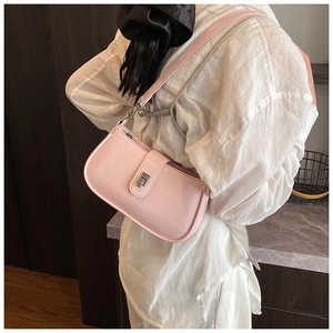 Close-up of pink faux leather crossbody bag with silver twist lock on a model