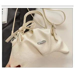 Détail de la texture cuir beige et boucle en métal argenté sur le sac à bandoulière